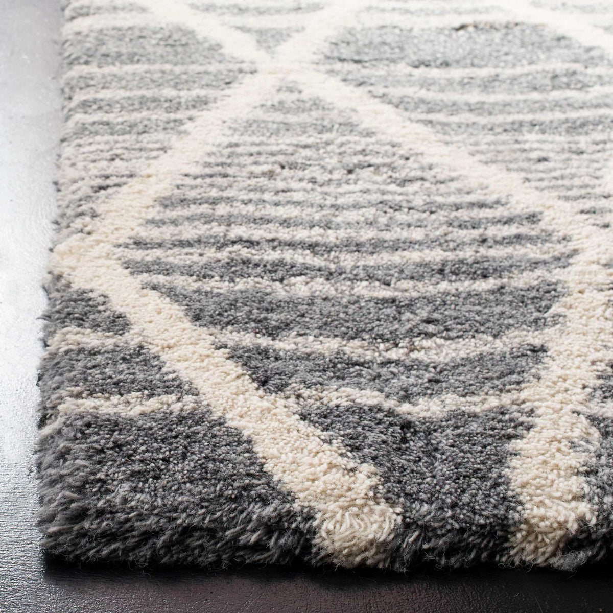 Dense gray wool pile and raised ivory lines create a cushioned, textured feel.