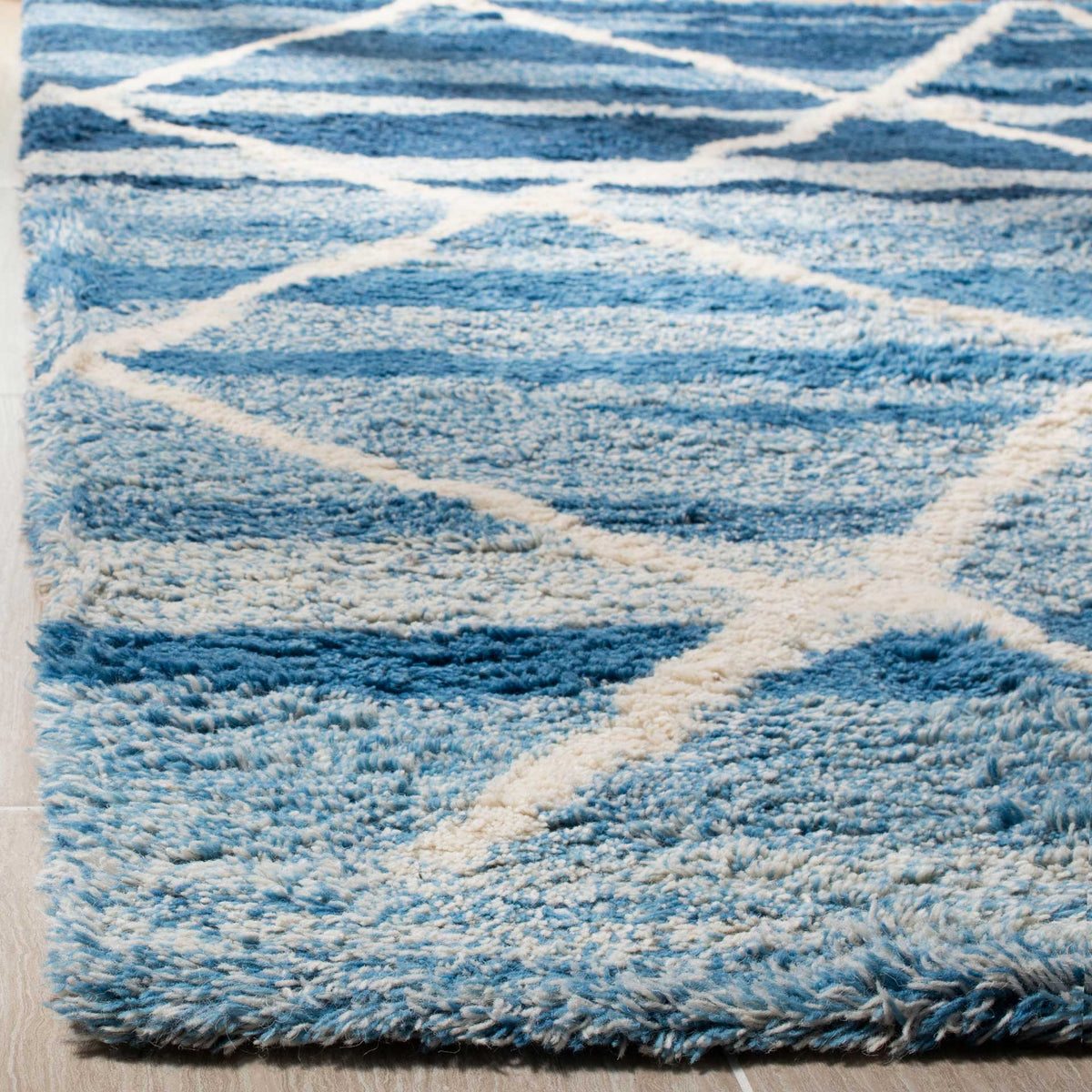 Thick blue wool pile and raised ivory lines add cozy dimension to the diamond design.
