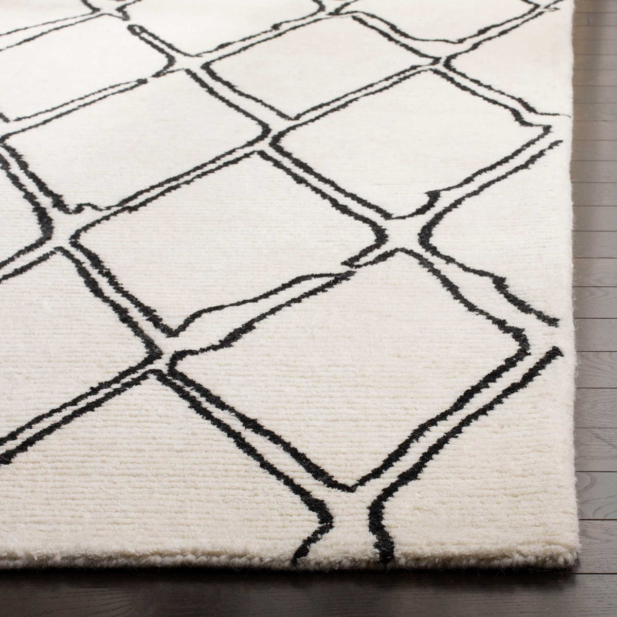 Plush ivory wool pile and black lattice lines meet at a neatly finished corner
