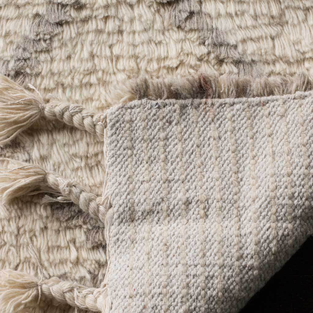 Woven underside and braided fringe complement the rug's plush ivory surface