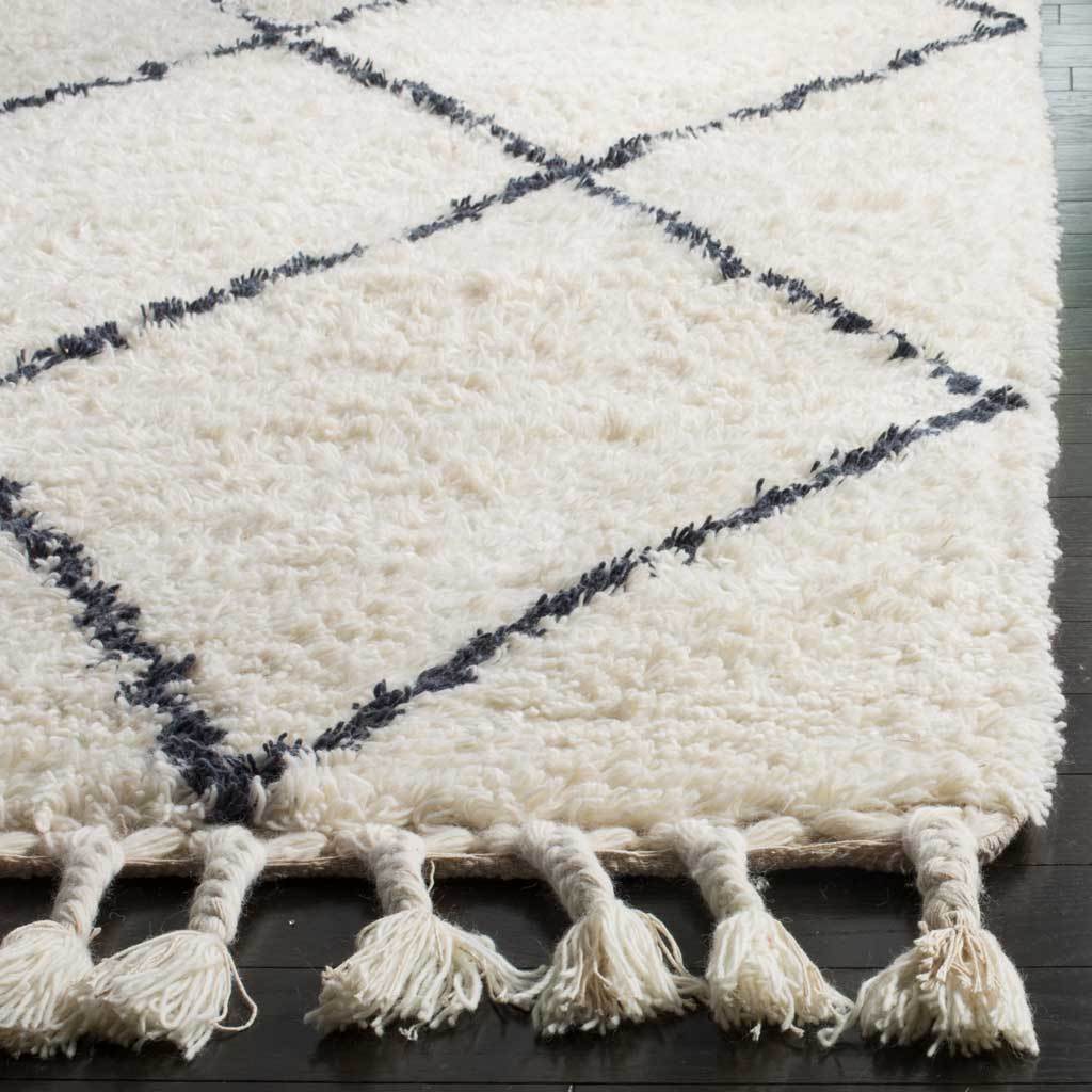 Thick ivory wool pile, dark gray lines and knotted fringe add rich texture.