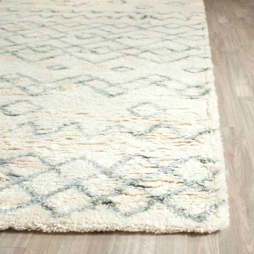 Dense ivory pile highlights soft blue lines and the rug's thick, cushioned edge