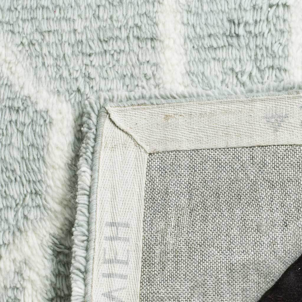 A folded corner reveals woven backing beneath the plush blue and ivory pile