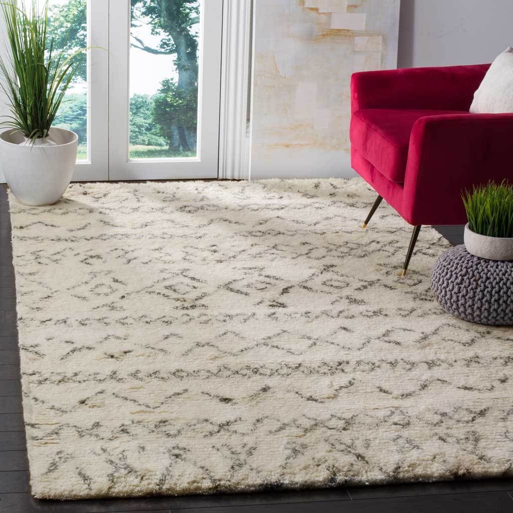 Plush ivory rug with soft gray geometric motifs adds warmth beneath a vivid accent chair