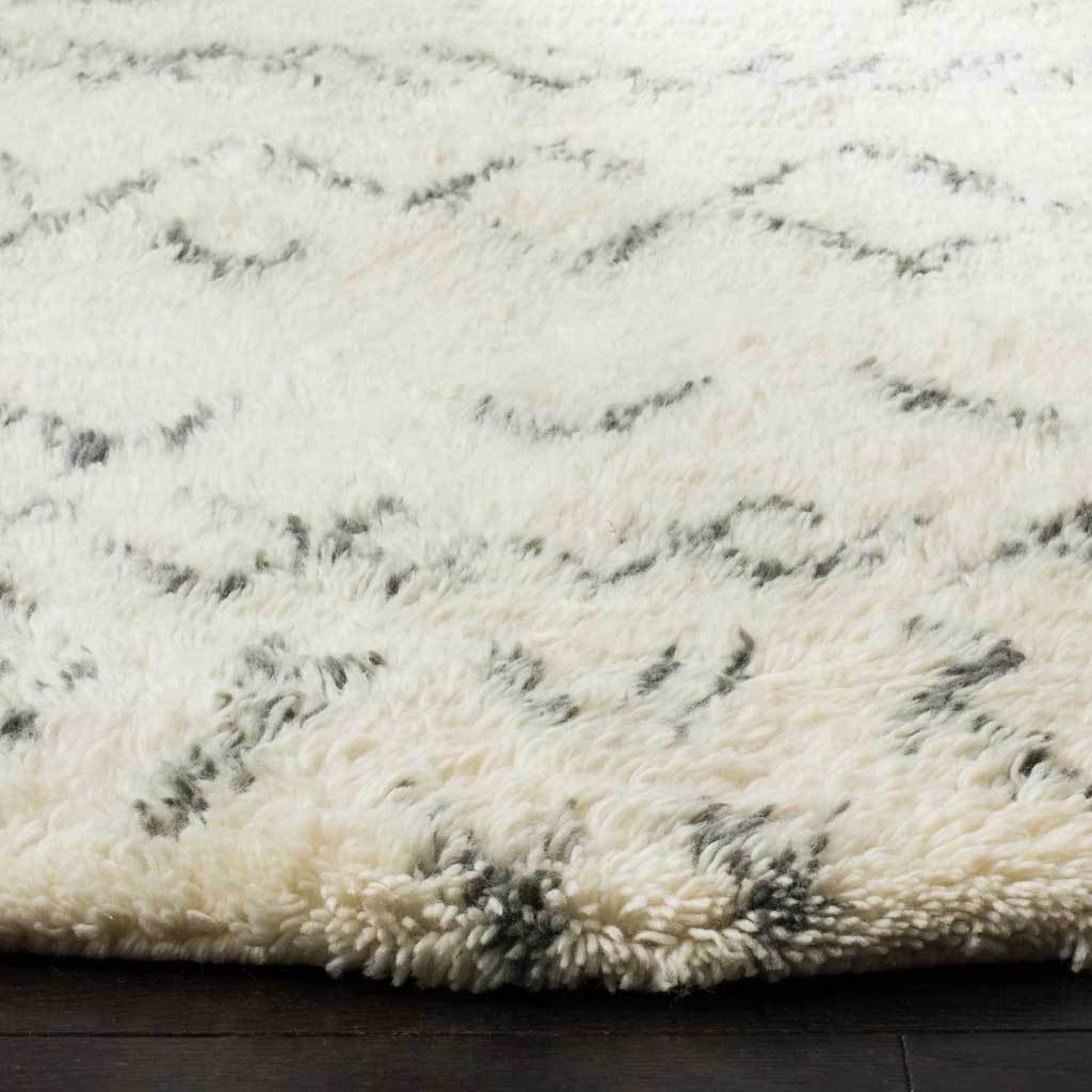 Thick ivory shag pile with gray accents creates a soft, cozy edge