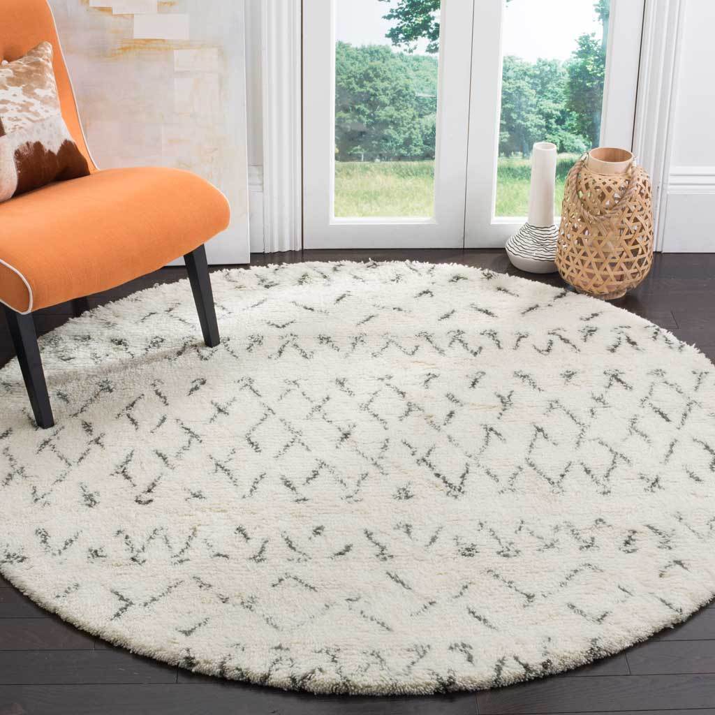 Round ivory rug brings scattered gray motifs and plush texture to a bright seating area