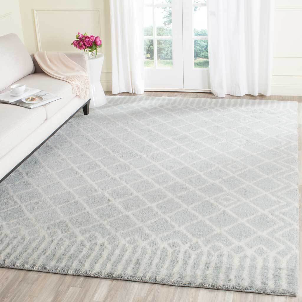 Pale blue diamond-patterned rug softens the floor beneath a light sofa