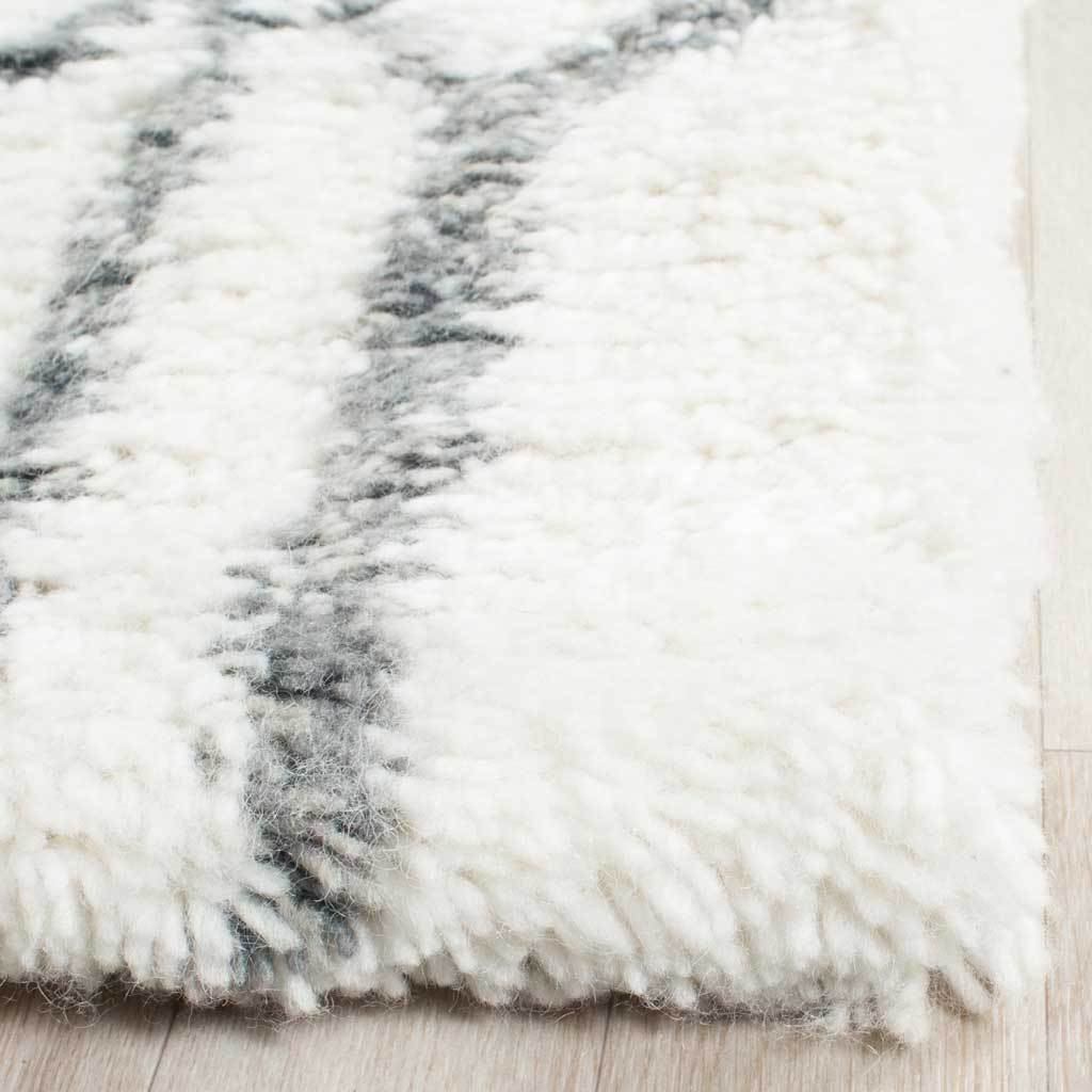 Plush ivory fibers and gray geometric lines meet at a thick rug corner