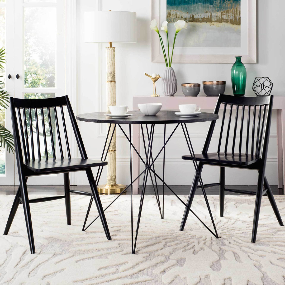 Two black spindle-back chairs bring clean-lined seating to a bright dining space with a round table.
