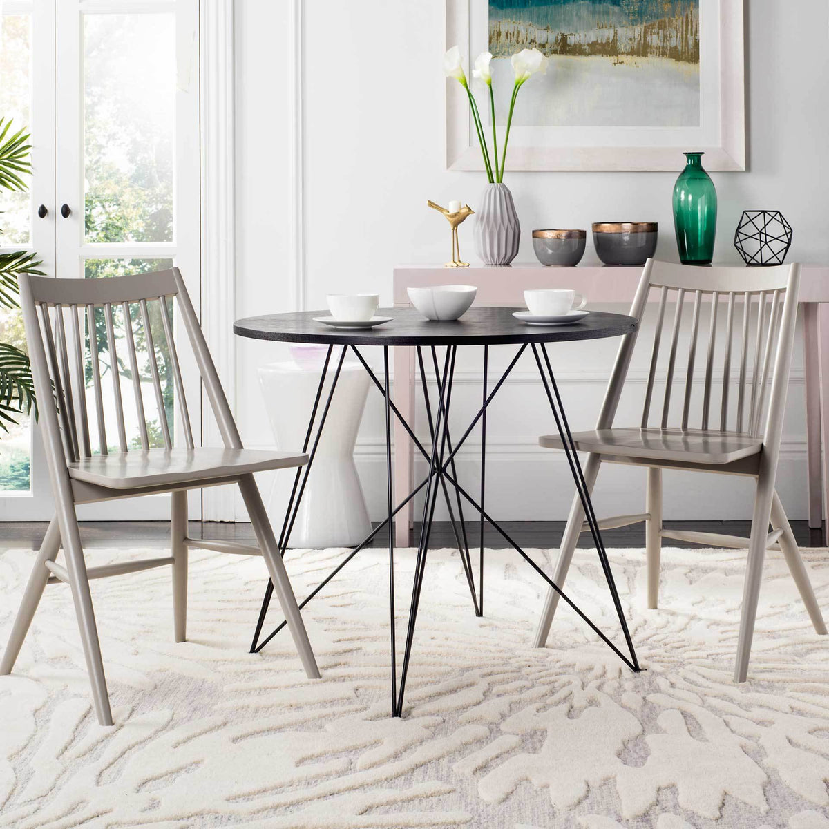 Two light gray spindle-back chairs flank a round dining table in an airy, bright room.