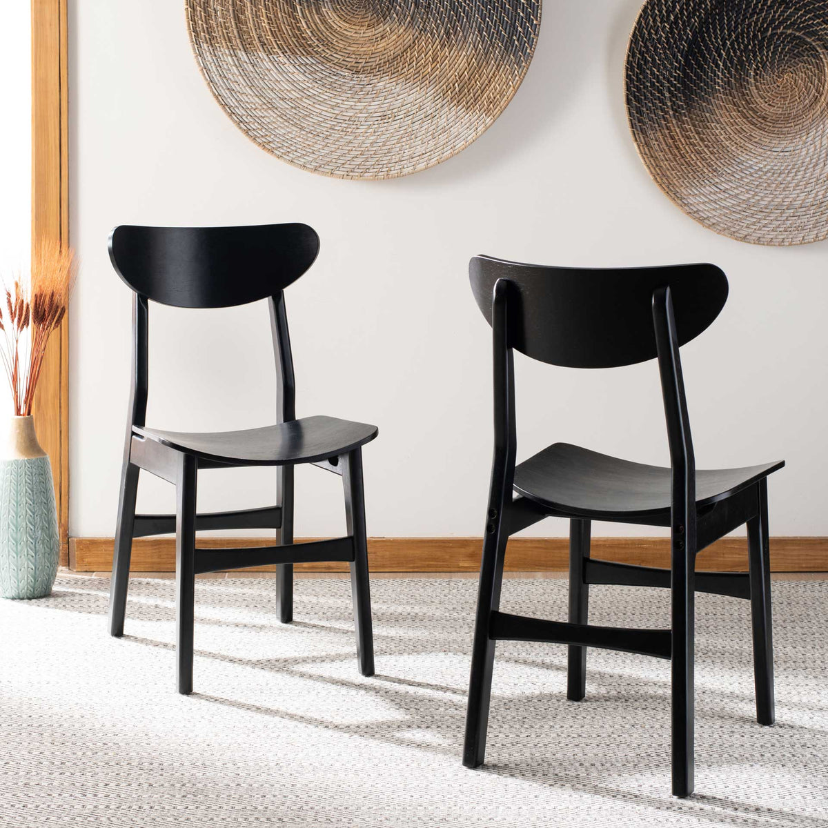 A pair of black wood dining chairs adds sculptural curved backs to a light, airy space