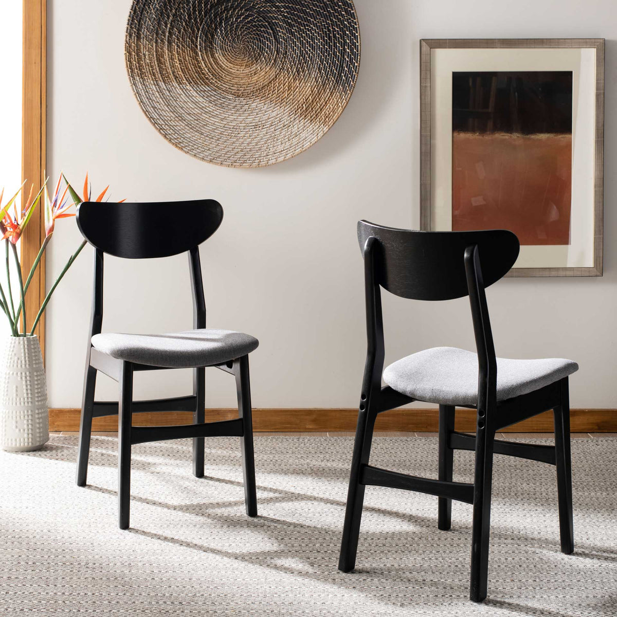 Black dining chairs with gray upholstered seats lend contrast to a bright room