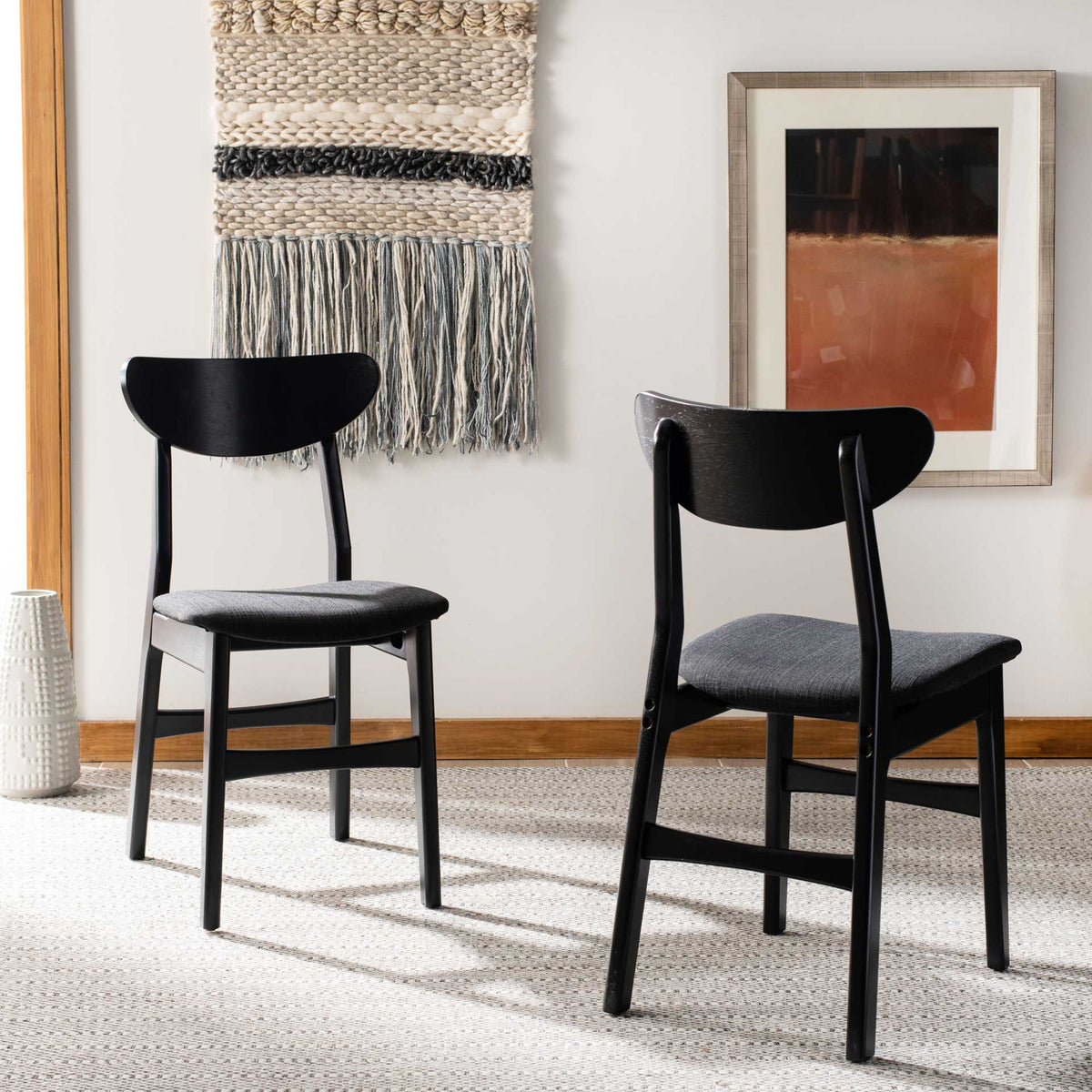 Black wood dining chairs pair curved backs and dark cushioned seats in a bright room