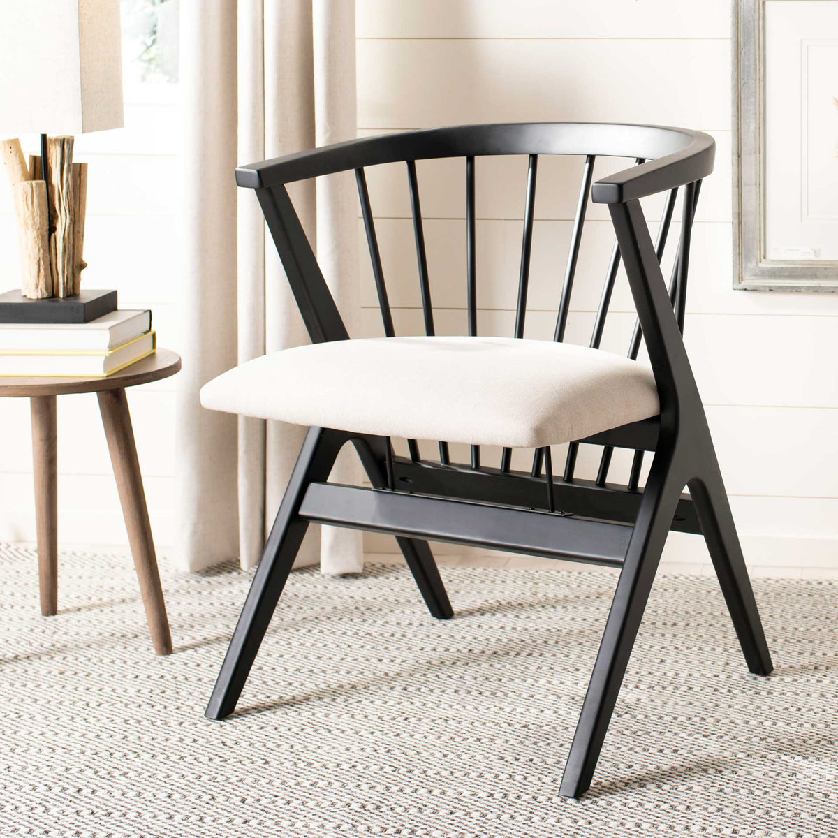 A black spindle-back chair balances clean geometric legs with a softly upholstered beige seat.