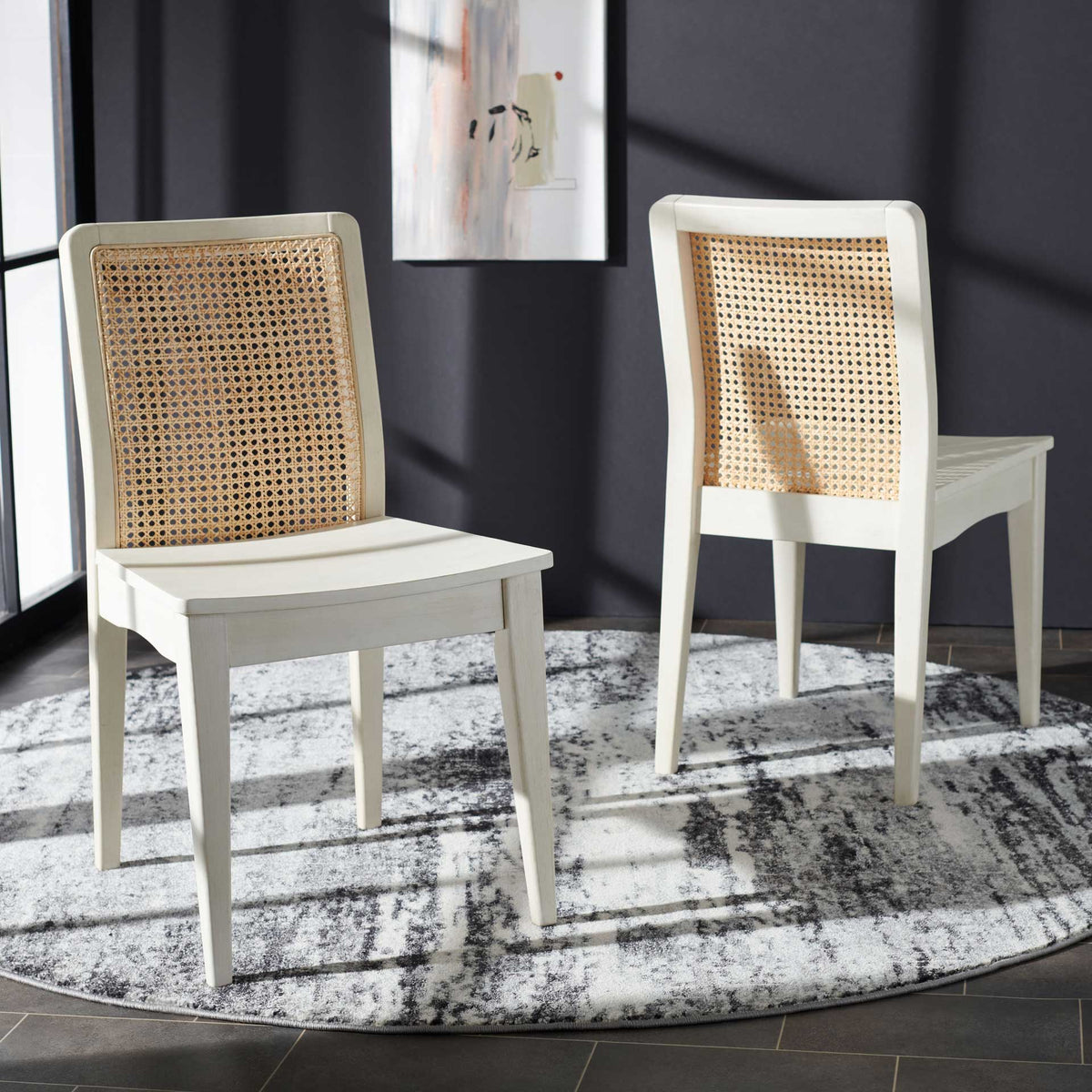 Two white wood dining chairs combine airy cane backs with a clean, relaxed silhouette