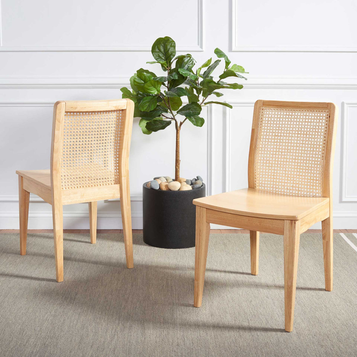 Two pale wood chairs with matching natural cane backs add warmth to a bright dining space