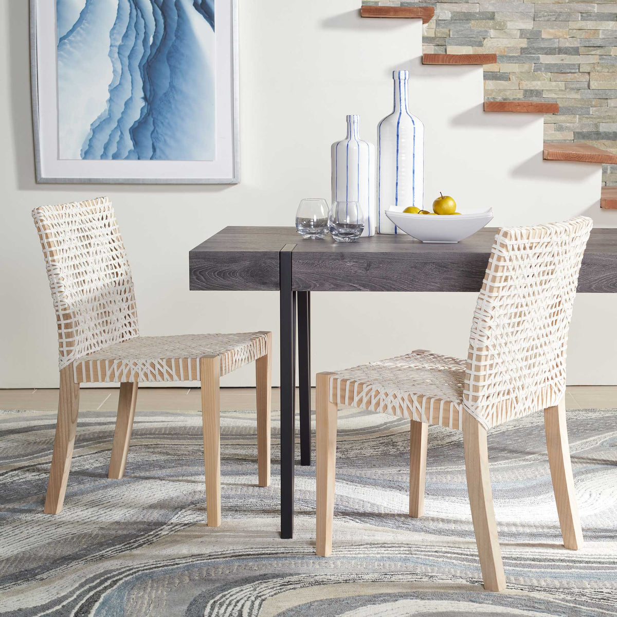 Woven white leather chairs bring airy texture beside a dark dining table, supported by natural teak frames