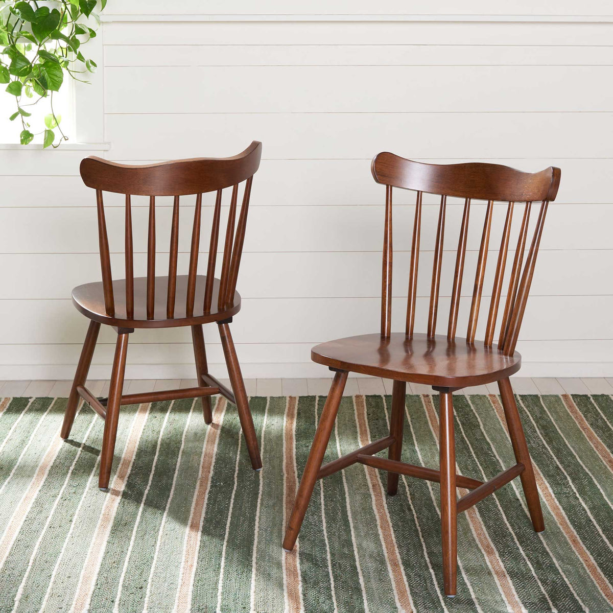 Matching walnut spindle-back chairs bring timeless charm to a bright space with a striped rug