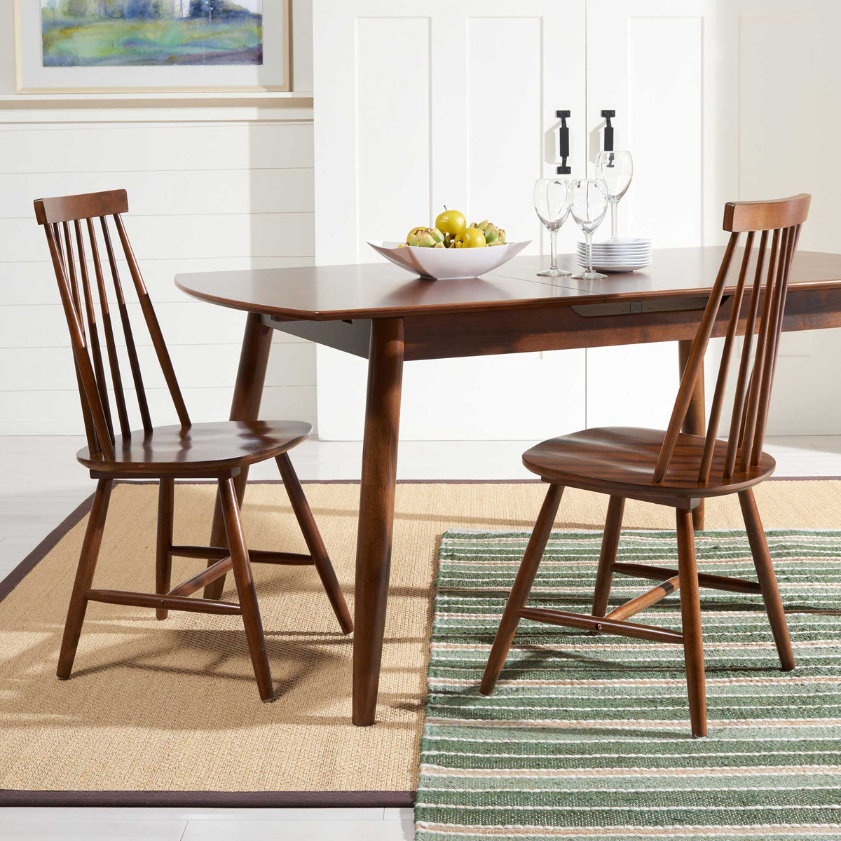 Two walnut dining chairs bring slender wooden spindles and warm tones to a welcoming dining table.