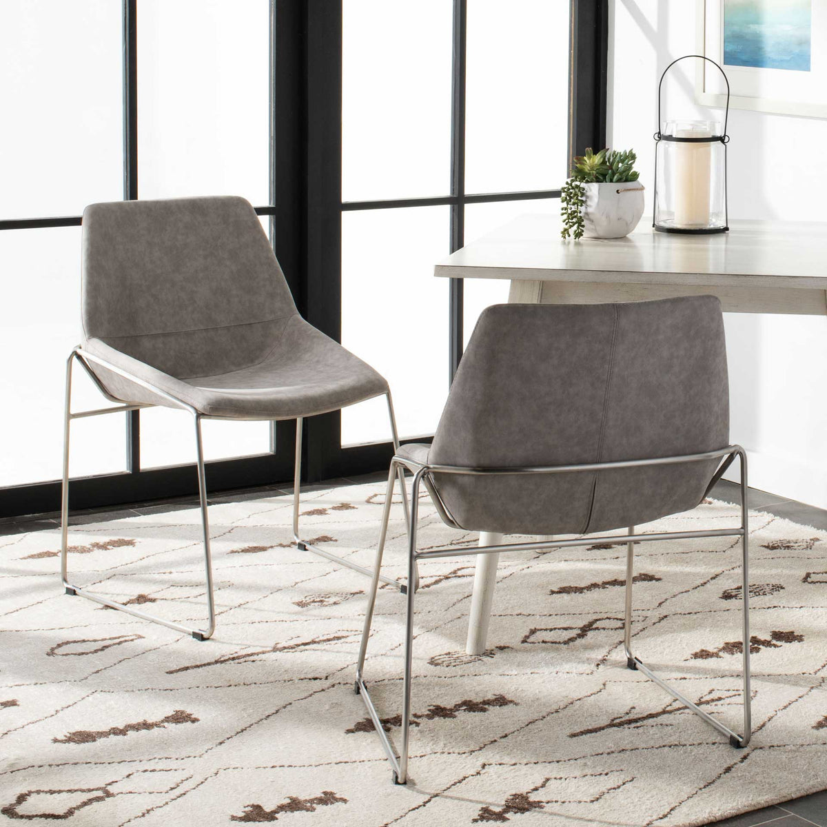 Stone gray upholstered chairs pair seamed backrests with slim silver sled-style bases