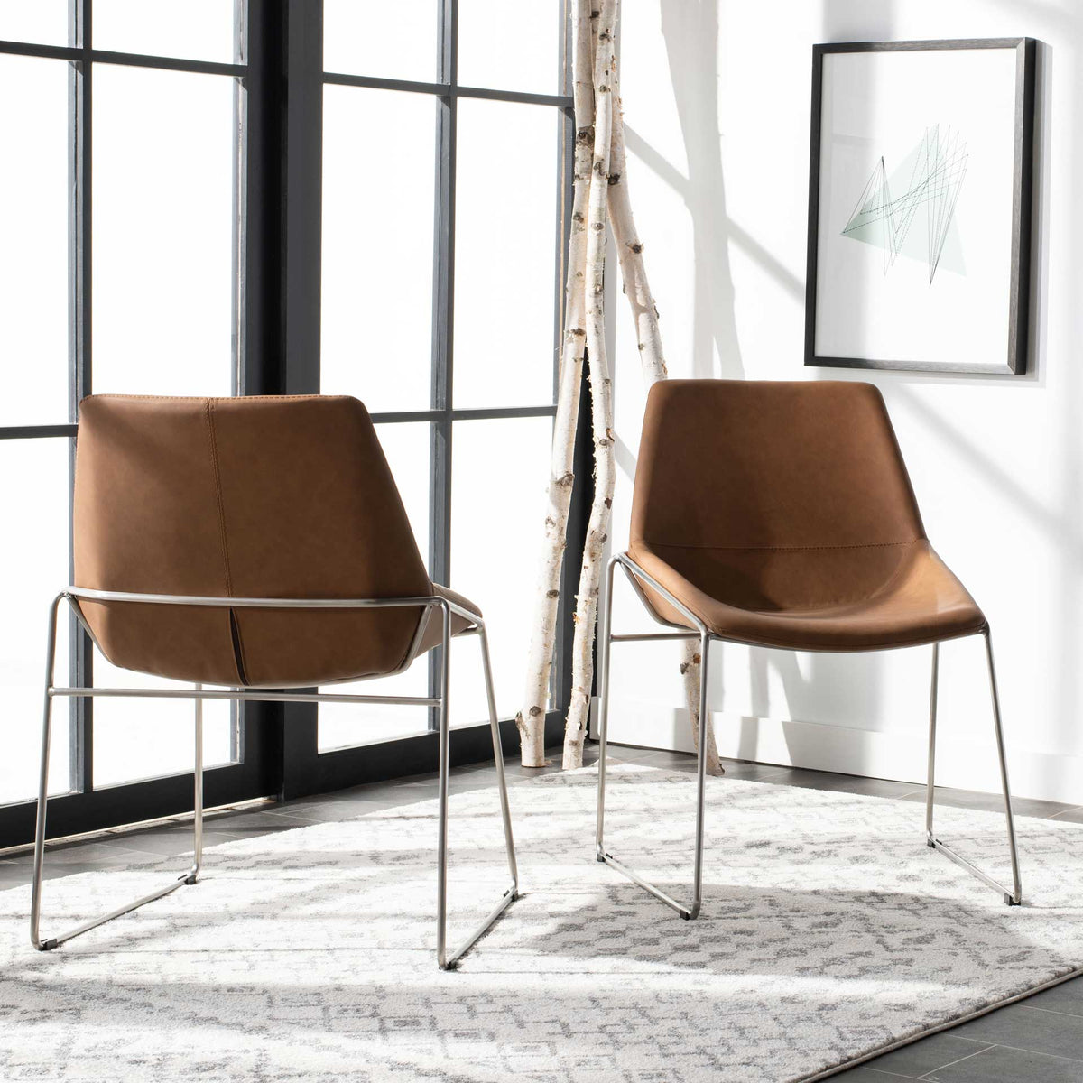 Matching cognac chairs offer sculpted faux leather seats and slim silver frames