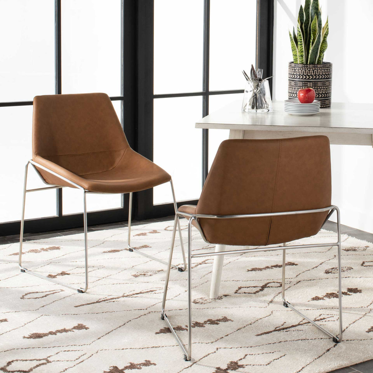 Stitched cognac backs complement the curved seats and silver frames of this matching chair pair