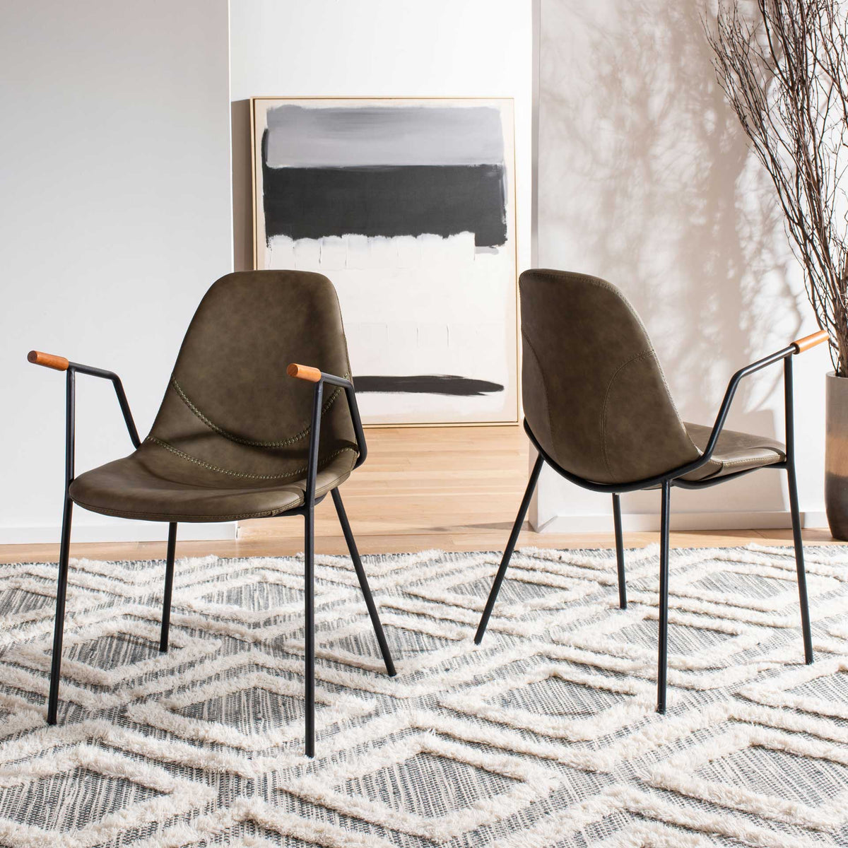 Two olive faux leather chairs create an airy pairing with sculpted seats and slim black metal legs