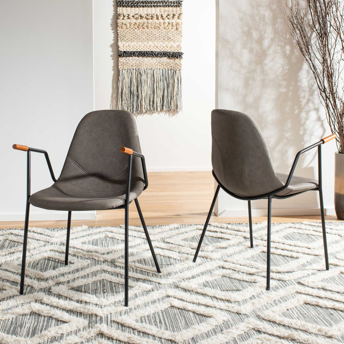 Two ash gray faux leather chairs feature curved seats, stitched backs, and slim black metal frames