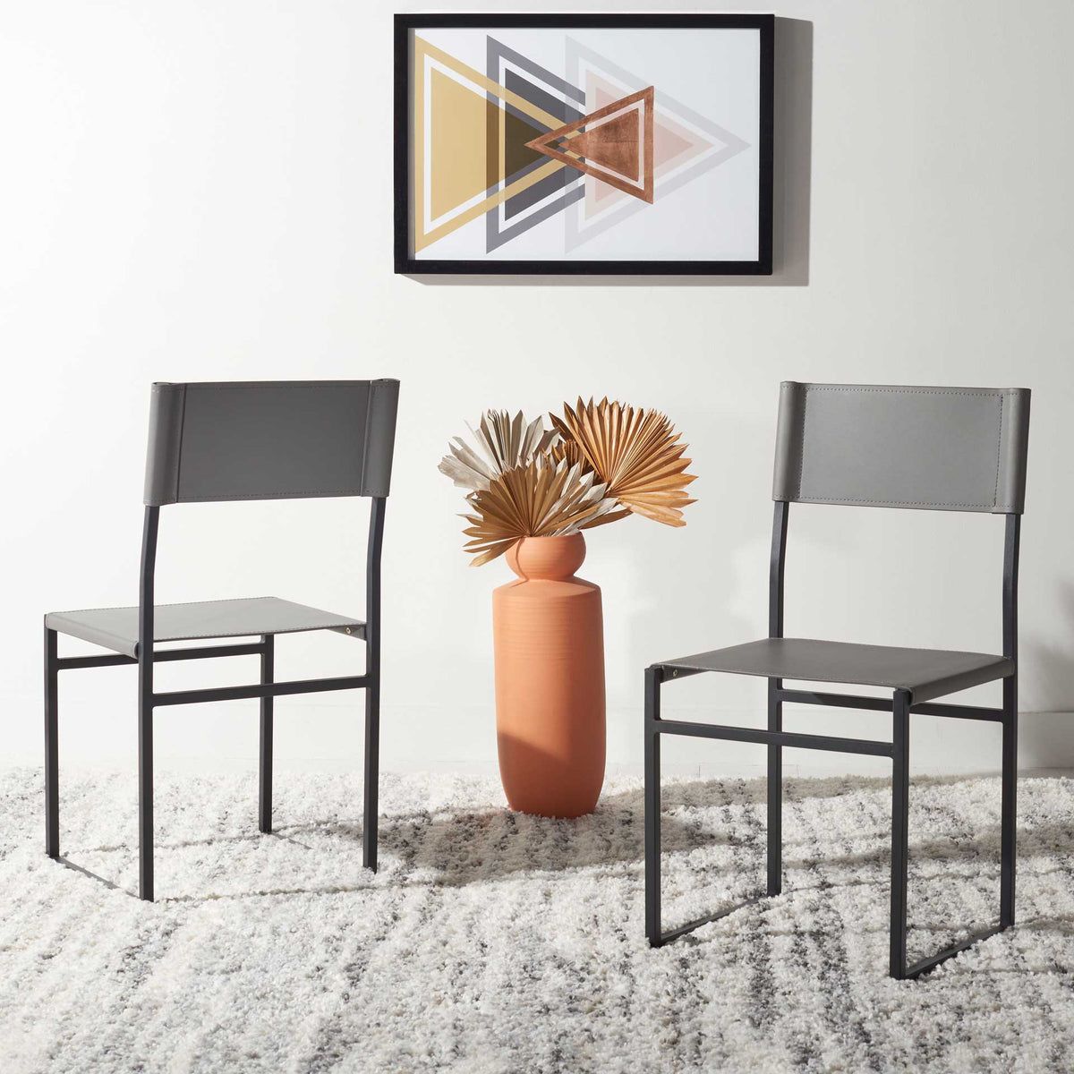 Two gray leather dining chairs lend understated color and airy metal lines to a modern room.