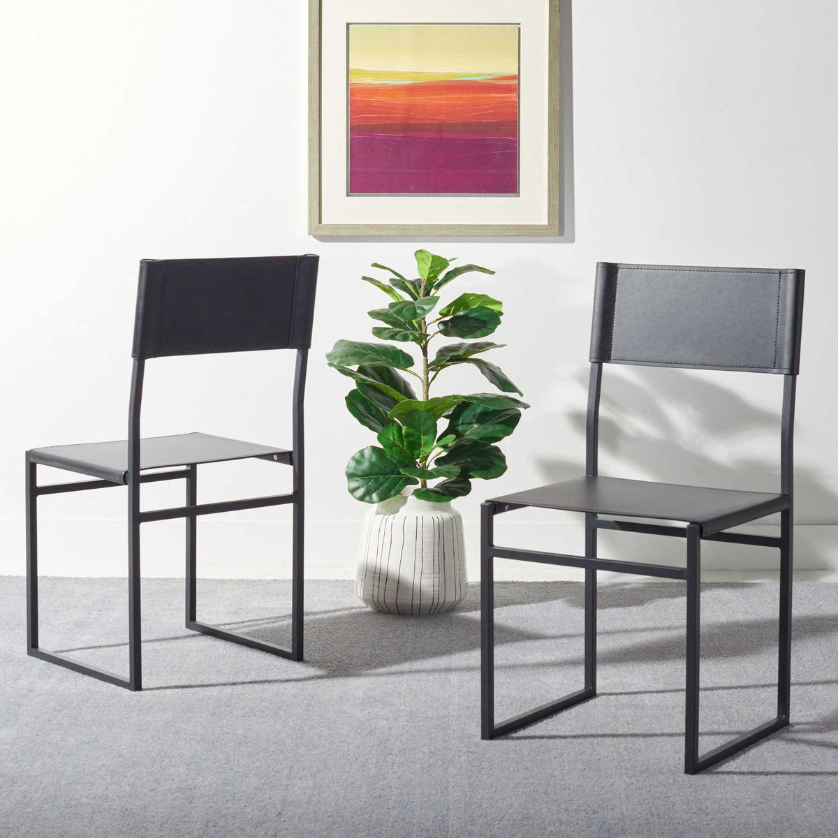 Two black leather dining chairs bring sleek open frames and simple stitched backs to a modern room.