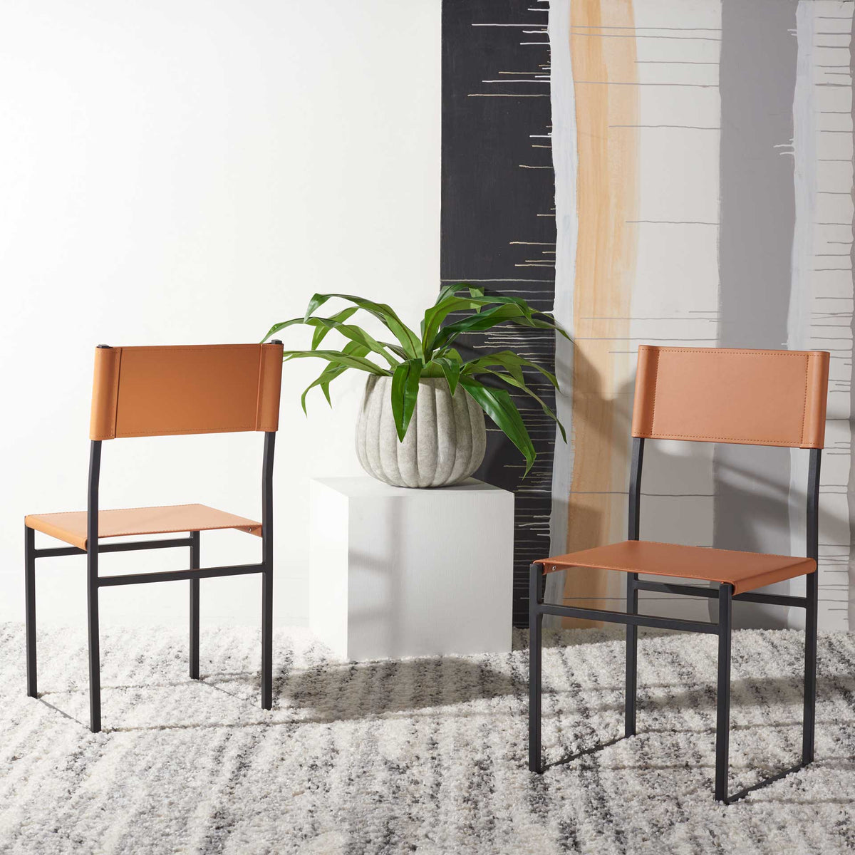 Two cognac leather chairs bring warm color and slender, open silhouettes to a contemporary room.