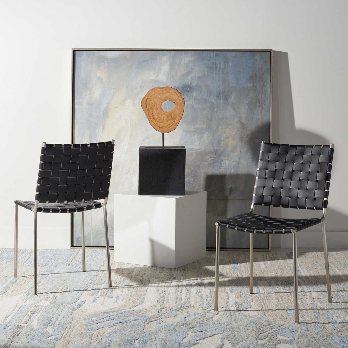 A pair of black leather dining chairs adds woven texture and slim silver accents to the space