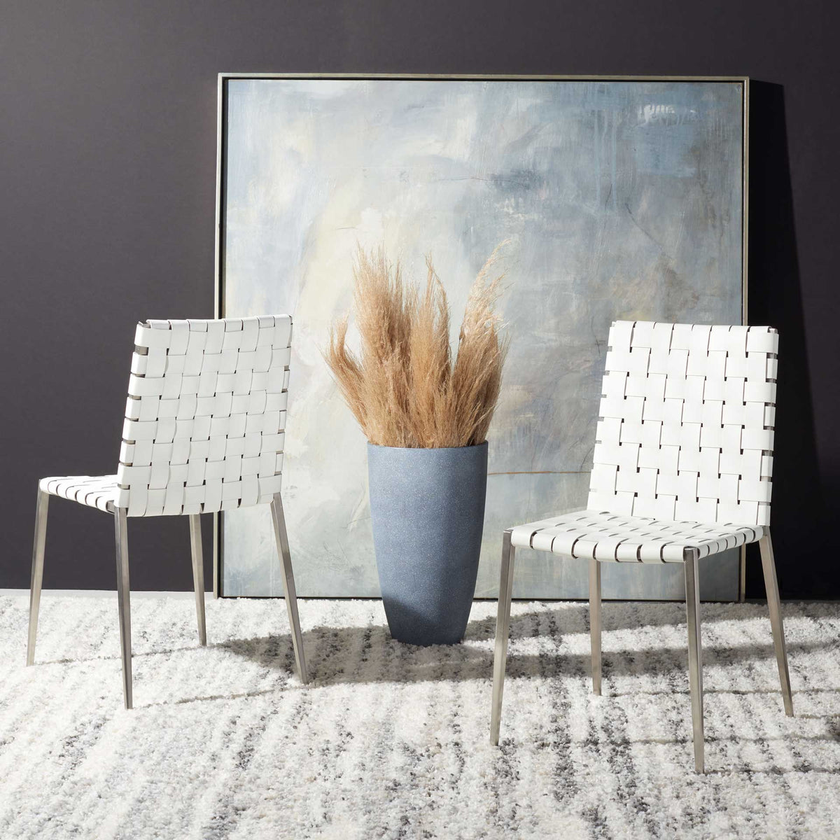 A pair of white woven chairs adds fresh texture and understated silver accents to the room.