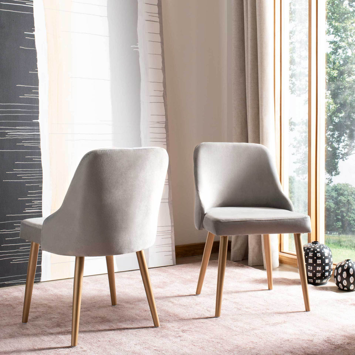 Two gray velvet chairs add plush texture and gold-tone accents to a bright interior.