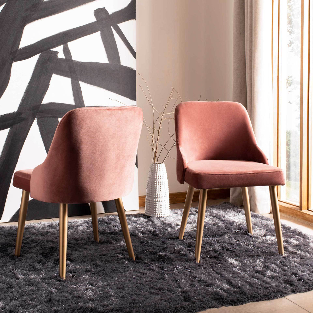 Two dusty rose velvet chairs bring rounded backs and gold-tone legs to a cozy interior.