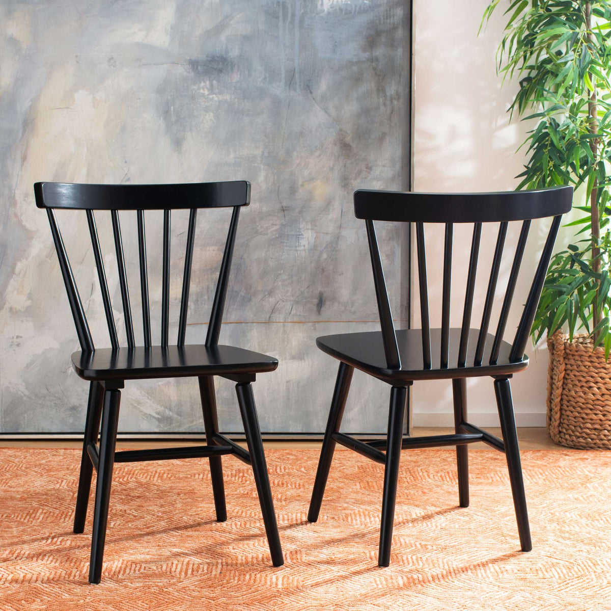 Two black spindle-back chairs add farmhouse character with splayed legs and smooth wood seats