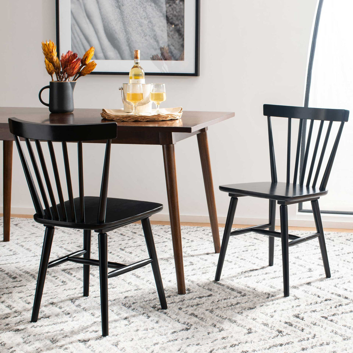 Two black dining chairs bring curved spindle backs and airy wood frames to the dining table