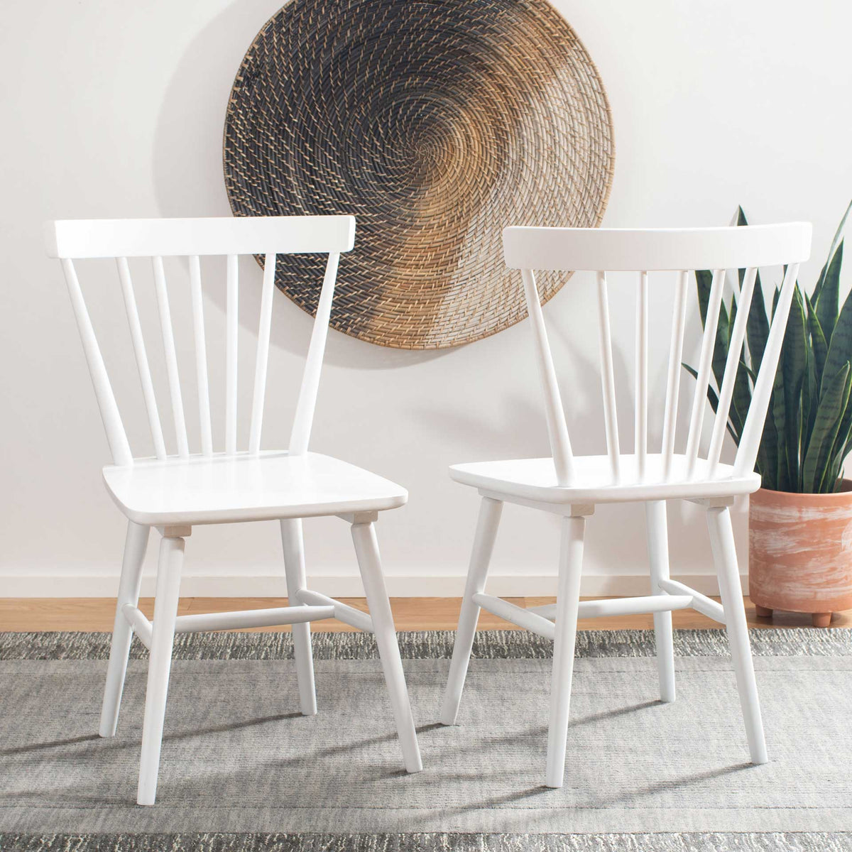 Two white spindle-back chairs bring a fresh, airy feel to a relaxed dining space
