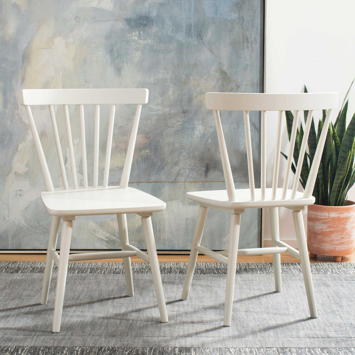 Two off-white dining chairs bring airy spindle backs and clean farmhouse lines to the room