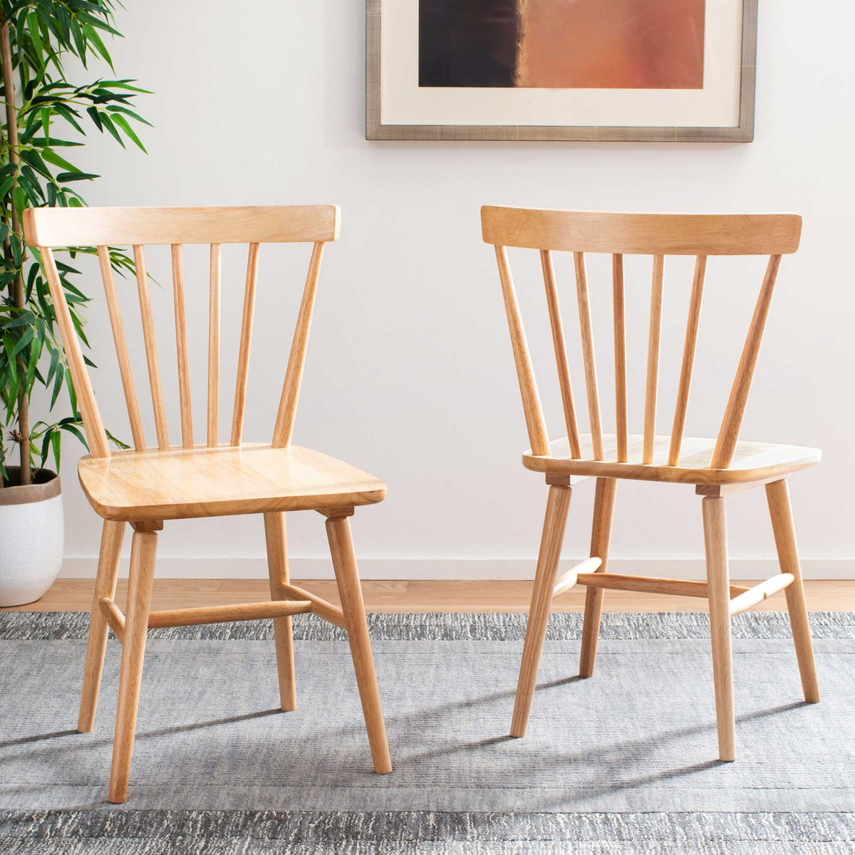 Two natural wood dining chairs bring warm grain and airy spindle backs to the room