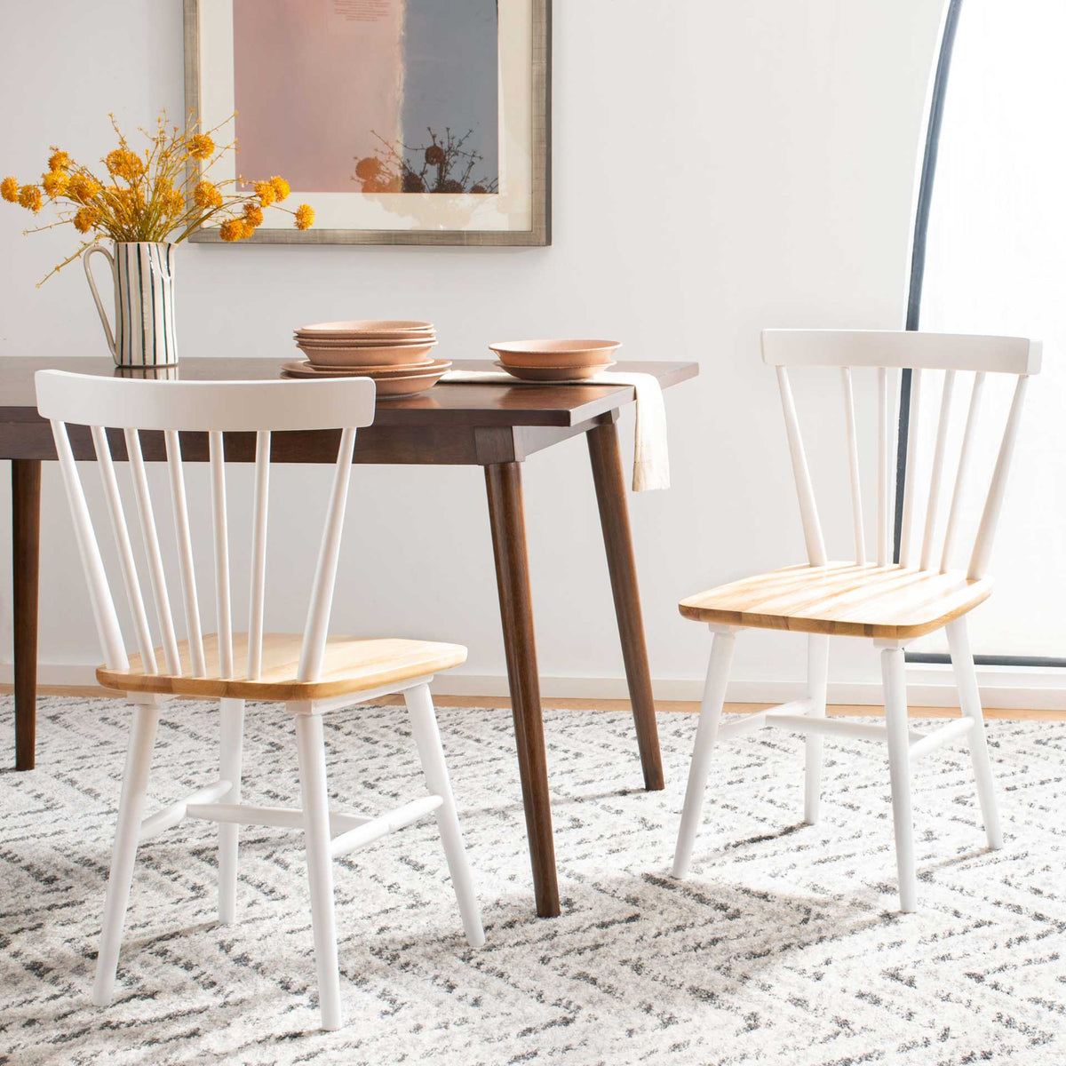 Two-tone dining chairs combine white spindle backs with warm wood seats around a table