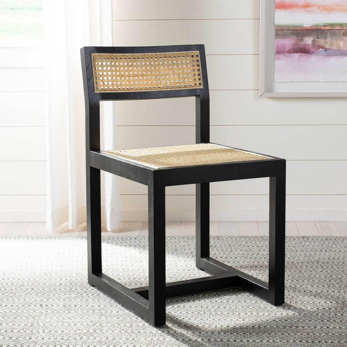 A black-finished elm chair with a woven cane seat and backrest brings warm contrast to a bright interior