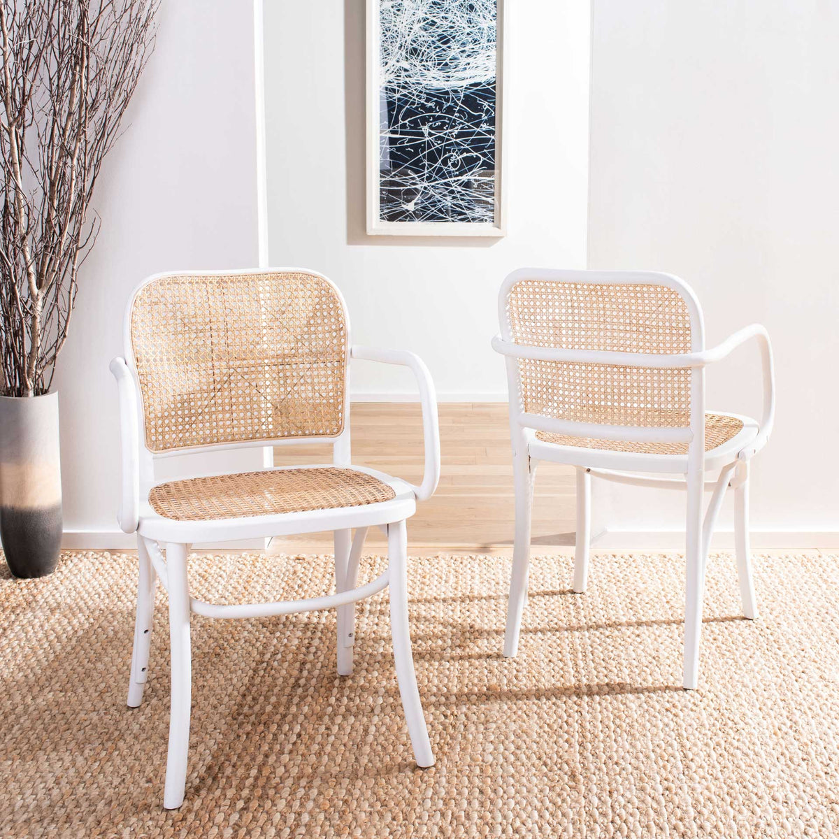 Two white wood chairs with natural cane seats and backs bring breezy texture to a bright interior.