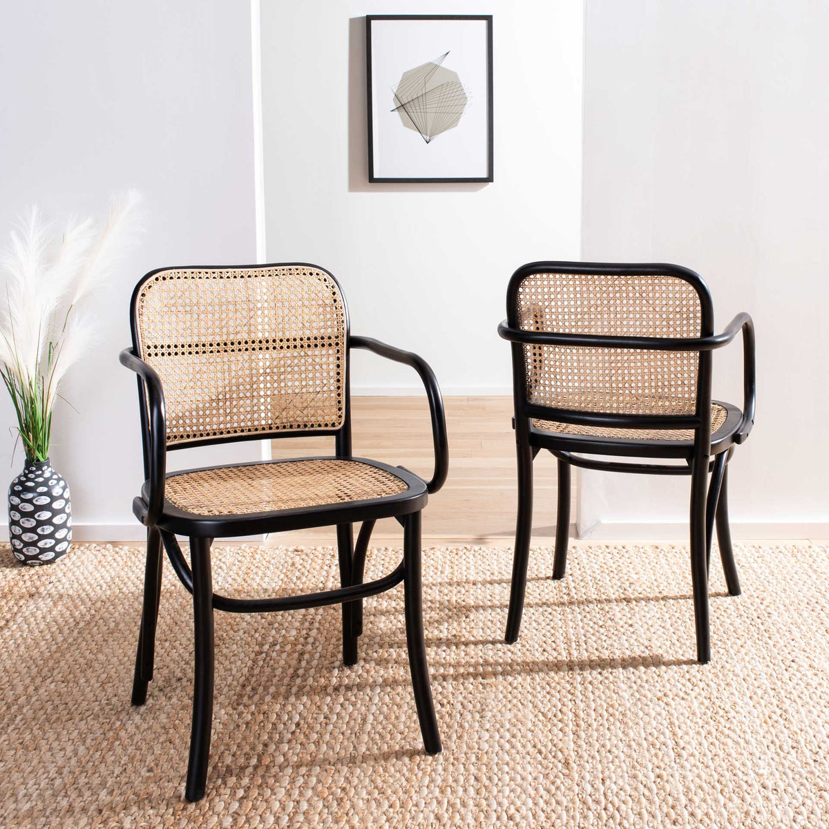 Two black wood dining chairs with natural cane seats and backs bring airy contrast to a bright interior.