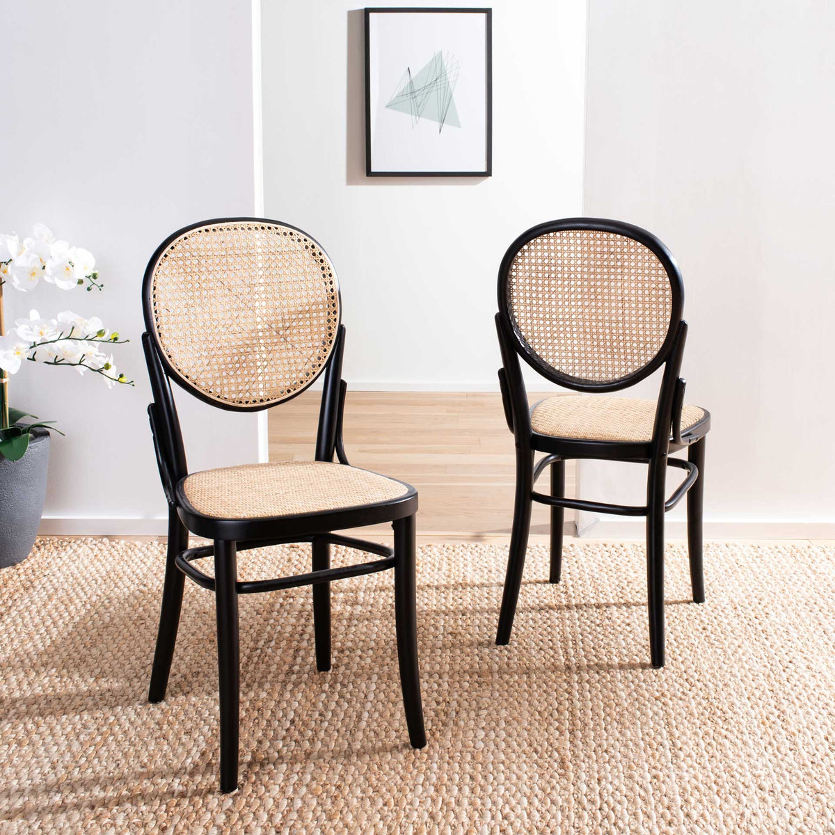 Two black-framed dining chairs bring airy cane texture and graceful curves to a dining space.