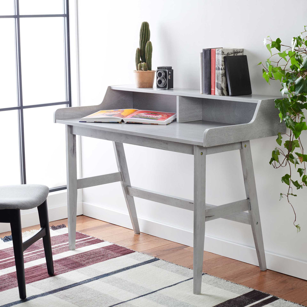 Gray desk with an elevated shelf for books and decor above a roomy workspace