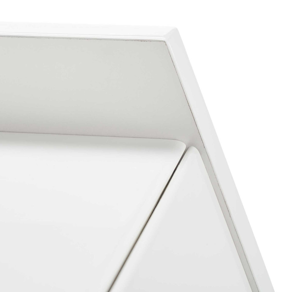 Smooth white lacquer and sharp beveled lines define the desk's upper corner.