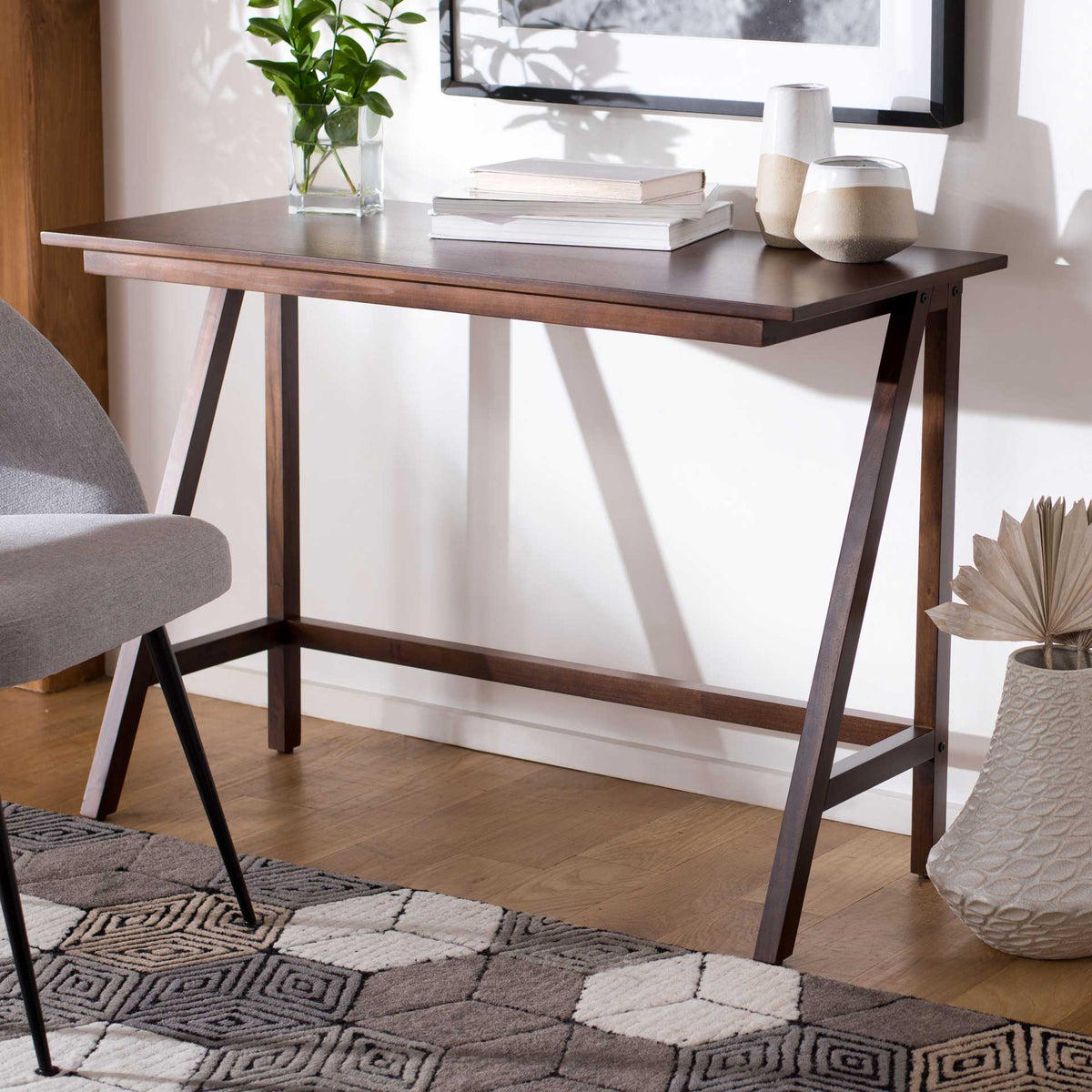 The walnut desk pairs a generous work surface with an open frame of slim, angled legs.