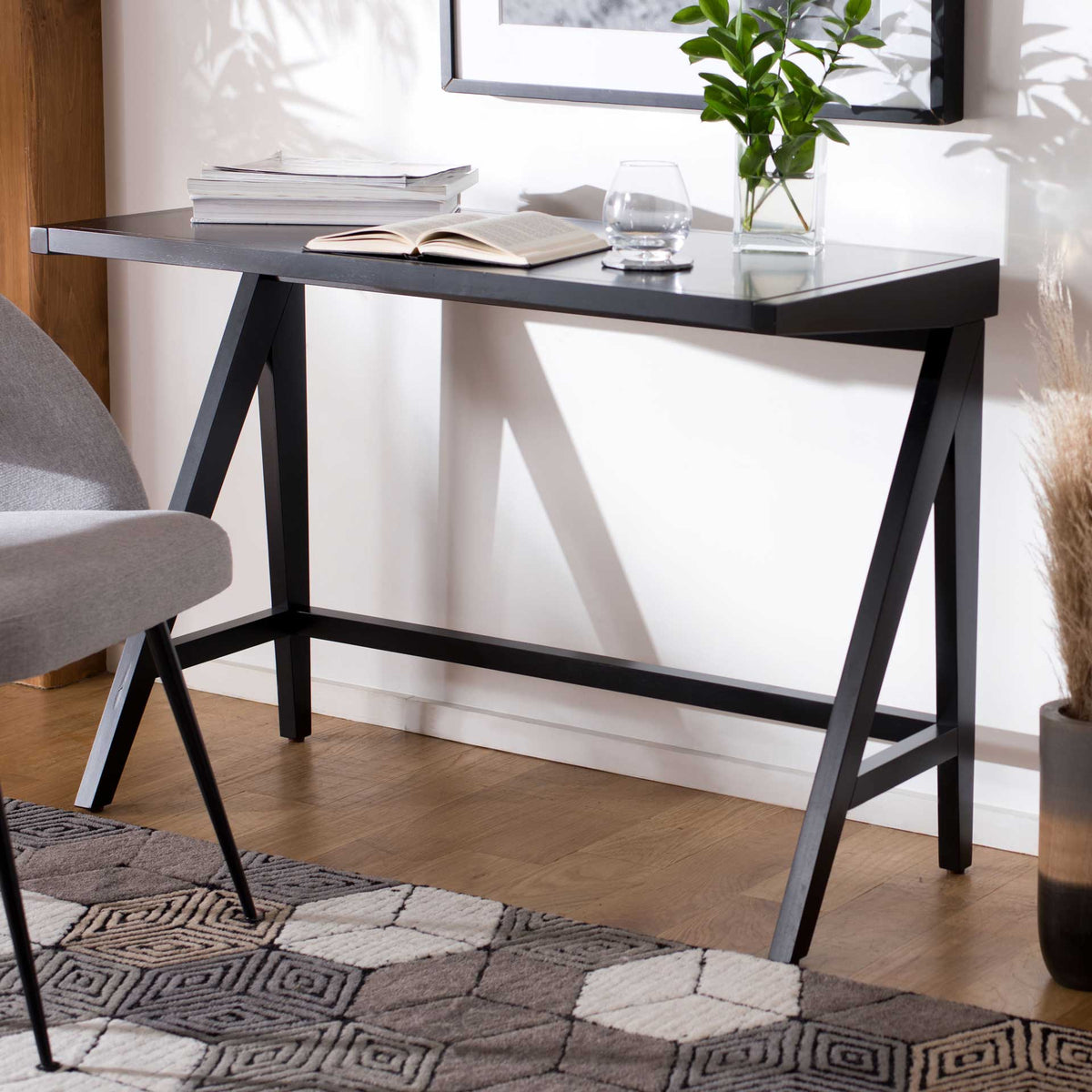 A compact black desk brings a sleek work surface and angled A-frame legs to a home office.