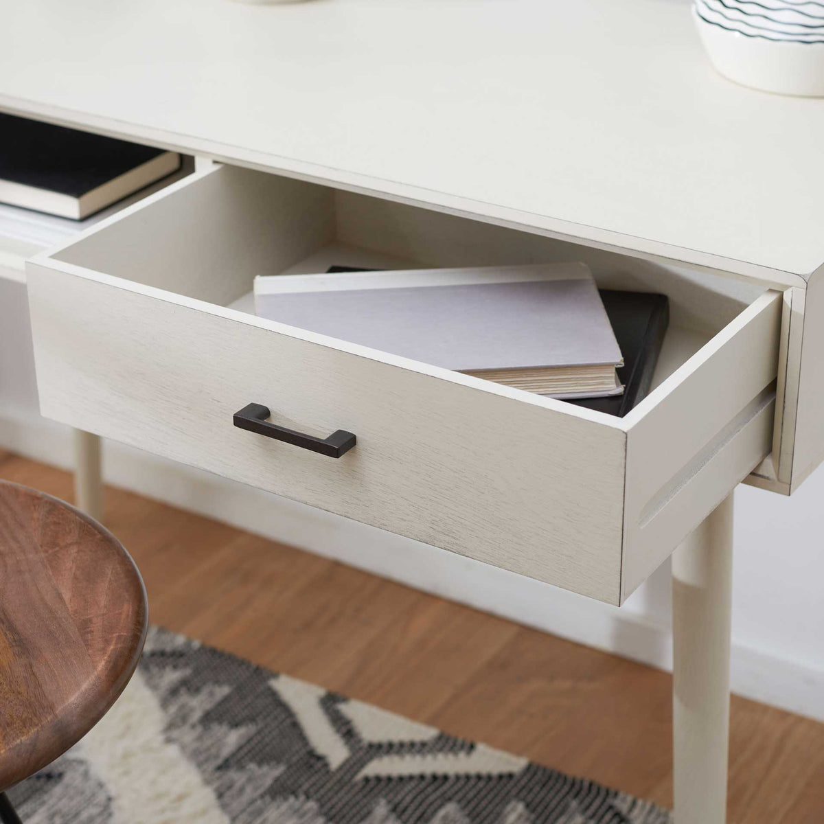 Open white desk drawer holds papers and notebooks within easy reach